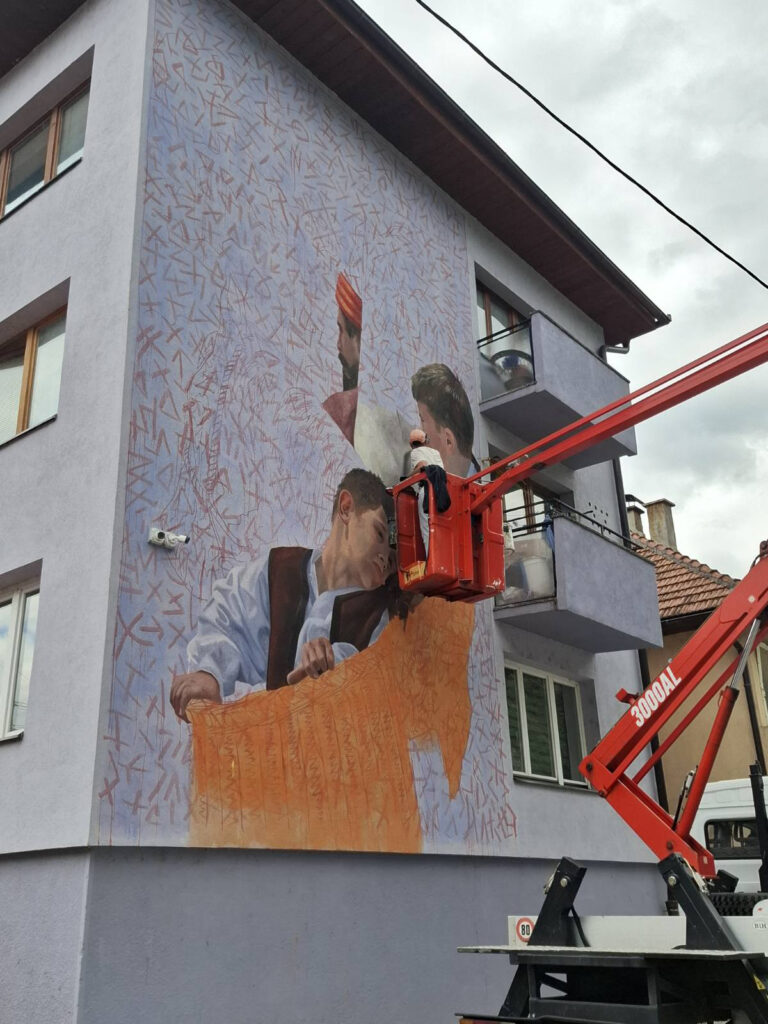 Artez oslikava mural o „Danku u krvi“ u blizini ćuprije na Drini
